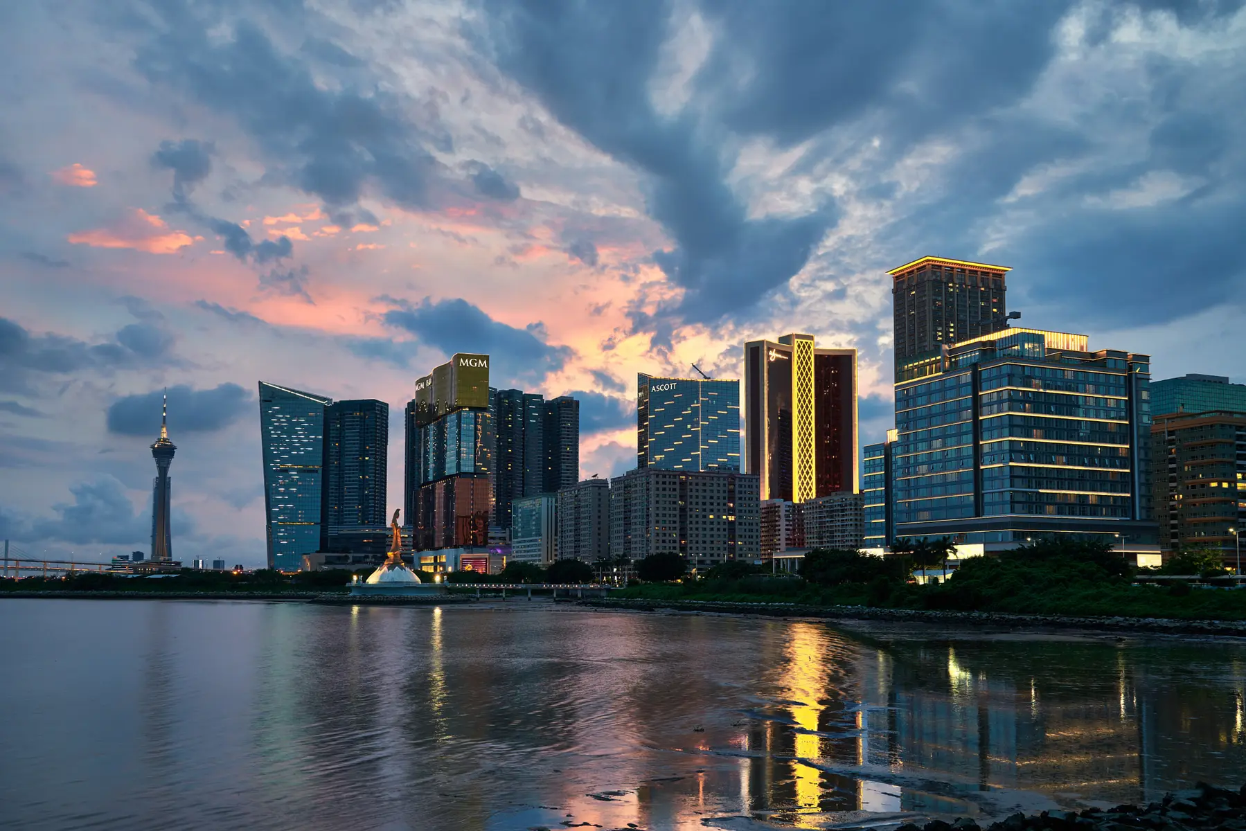 Die Skyline von Macau bei Sonnenuntergang mit beleuchteten Hotels und dem Macao Tower im Hintergrund.