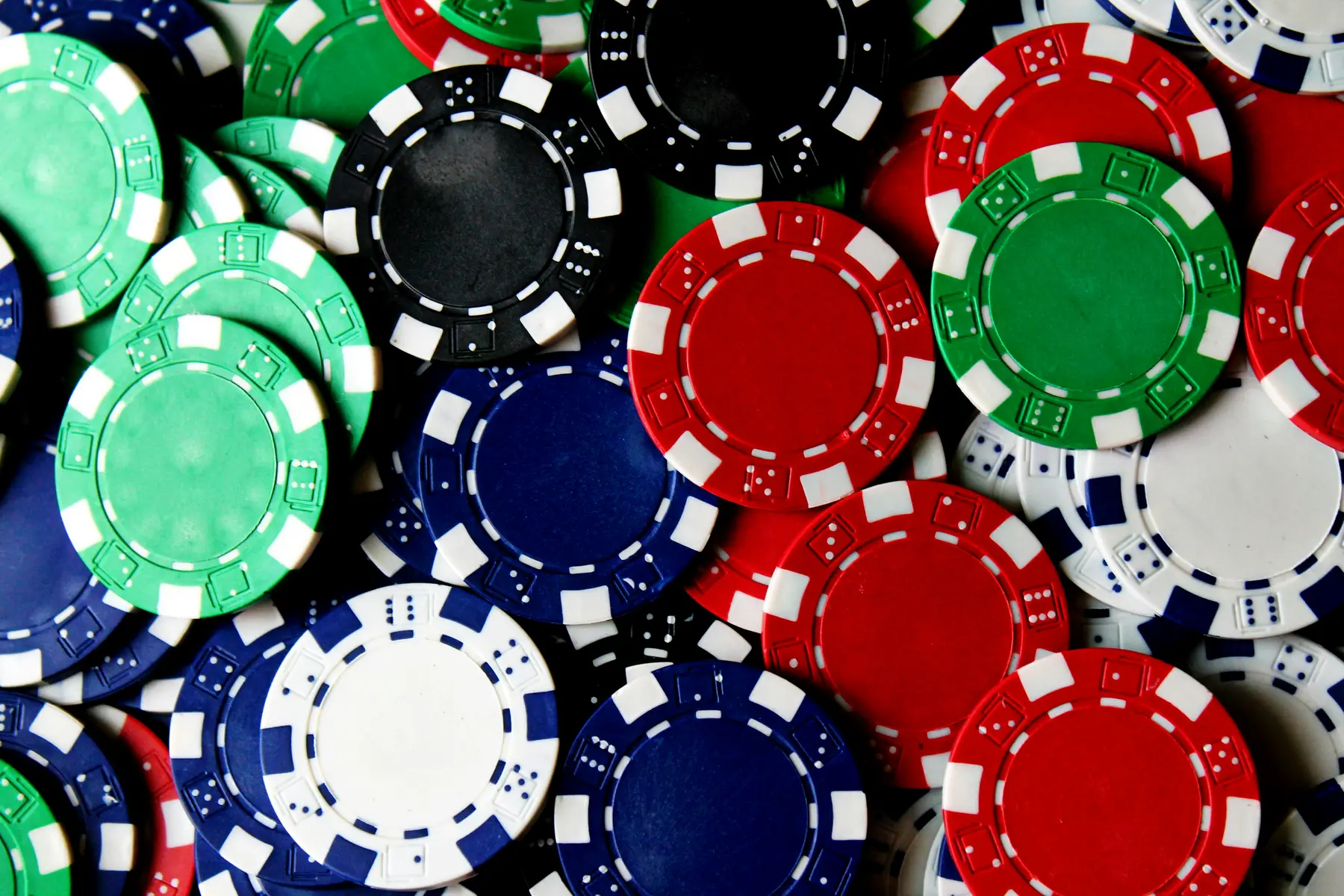 Eine Ansammlung von bunten Pokerchips in Rot, Grün, Blau und Schwarz.