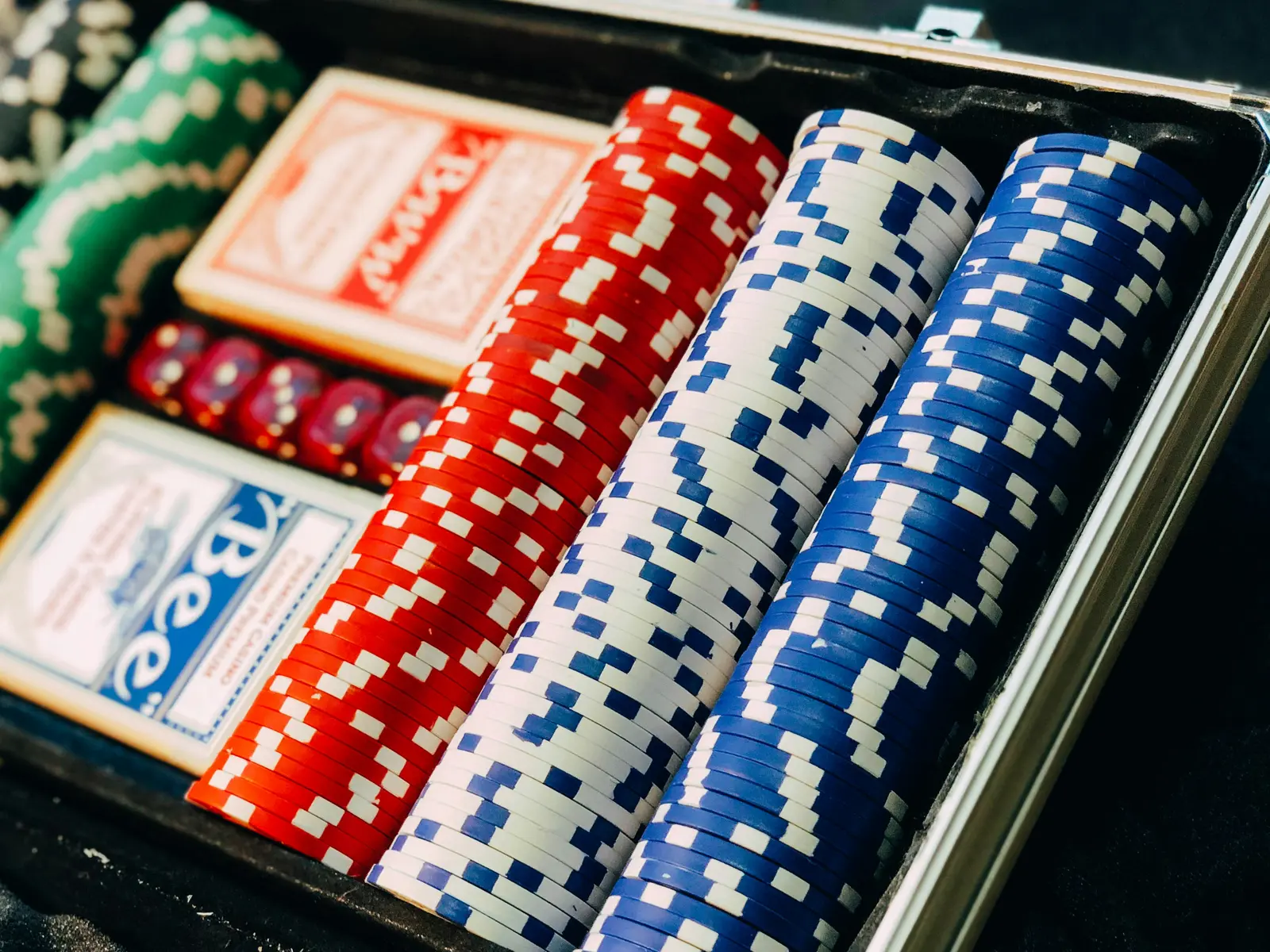 Eine Auswahl an bunten Pokerchips und Spielkarten in einem Koffer.