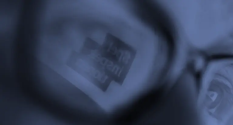 Spelinspektionens logotyp speglas i glasögon framför ett öga i närbild.