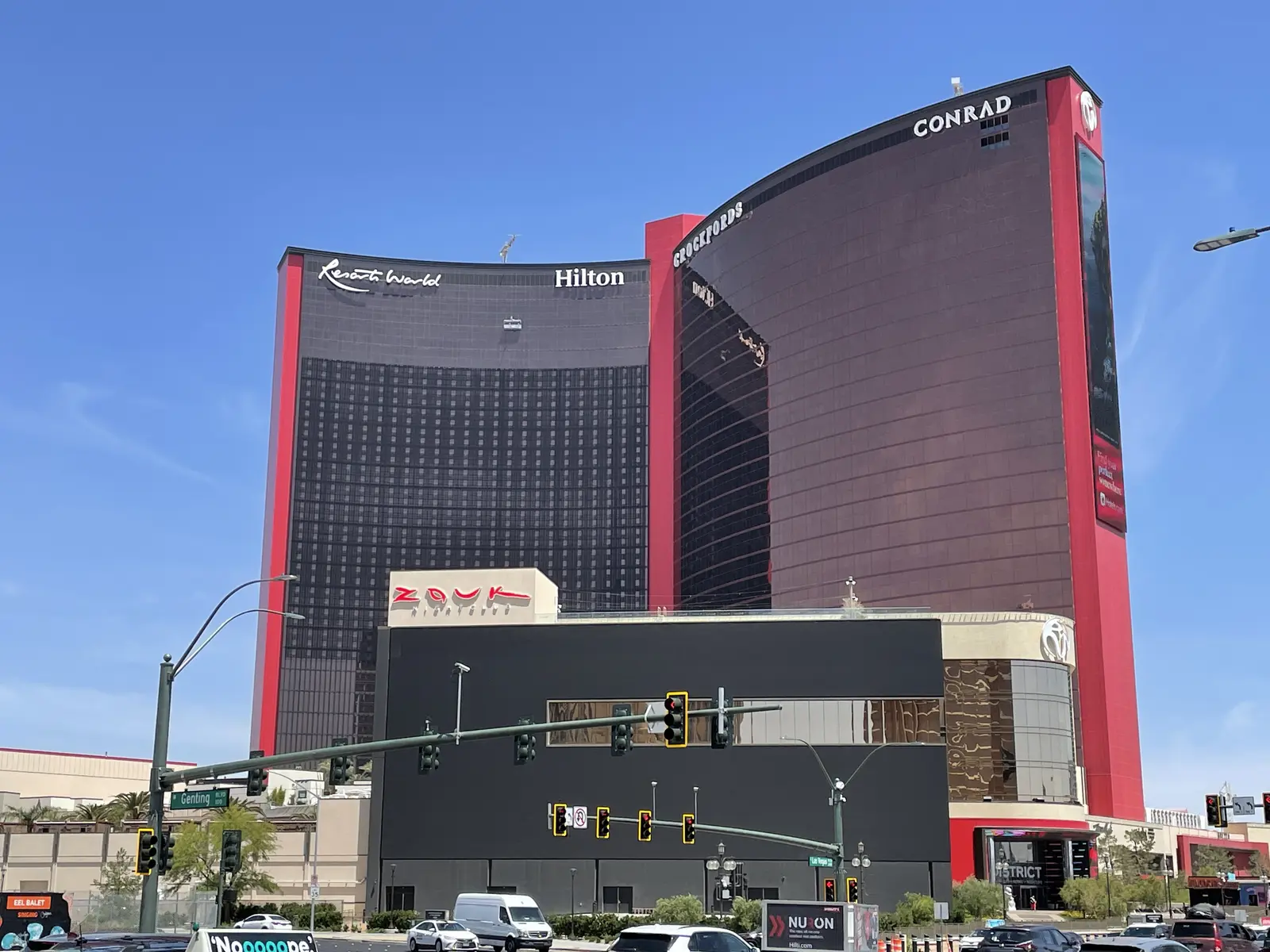 Exteriör av Resorts World Las Vegas med hotellbyggnaderna Hilton och Conrad under en blå himmel.