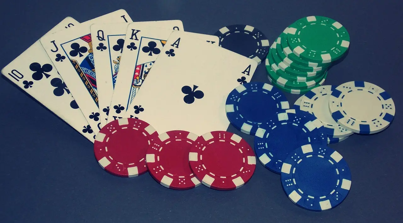 En royal flush i klöver med tillhörande pokerchips på ett bord