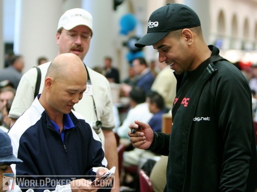 Shooting Star David Williams (right) autographs a playing card for Chanh Pham, who busted him for a $5,000 bounty on Day 1a of the WPT Bay 101 Shooting Star Tournament