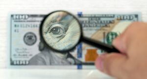 A picture of a magnifying glass over a $100 bill