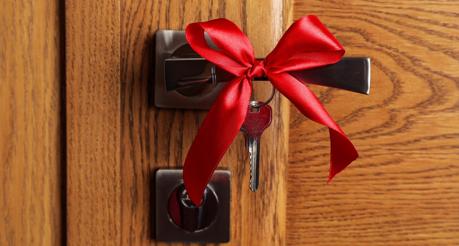 A picture of a house's front door with a bow wrapped around the key