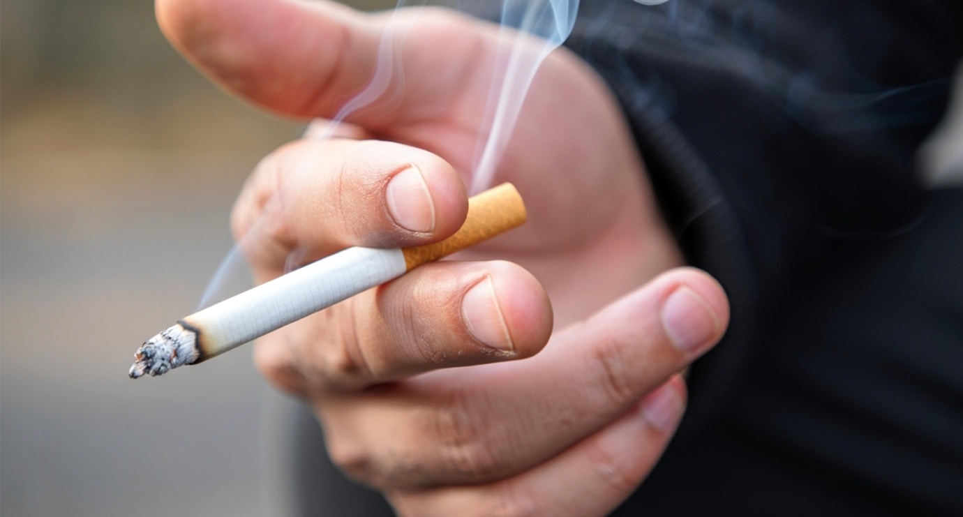 A picture of a hand holding a lit cigarette